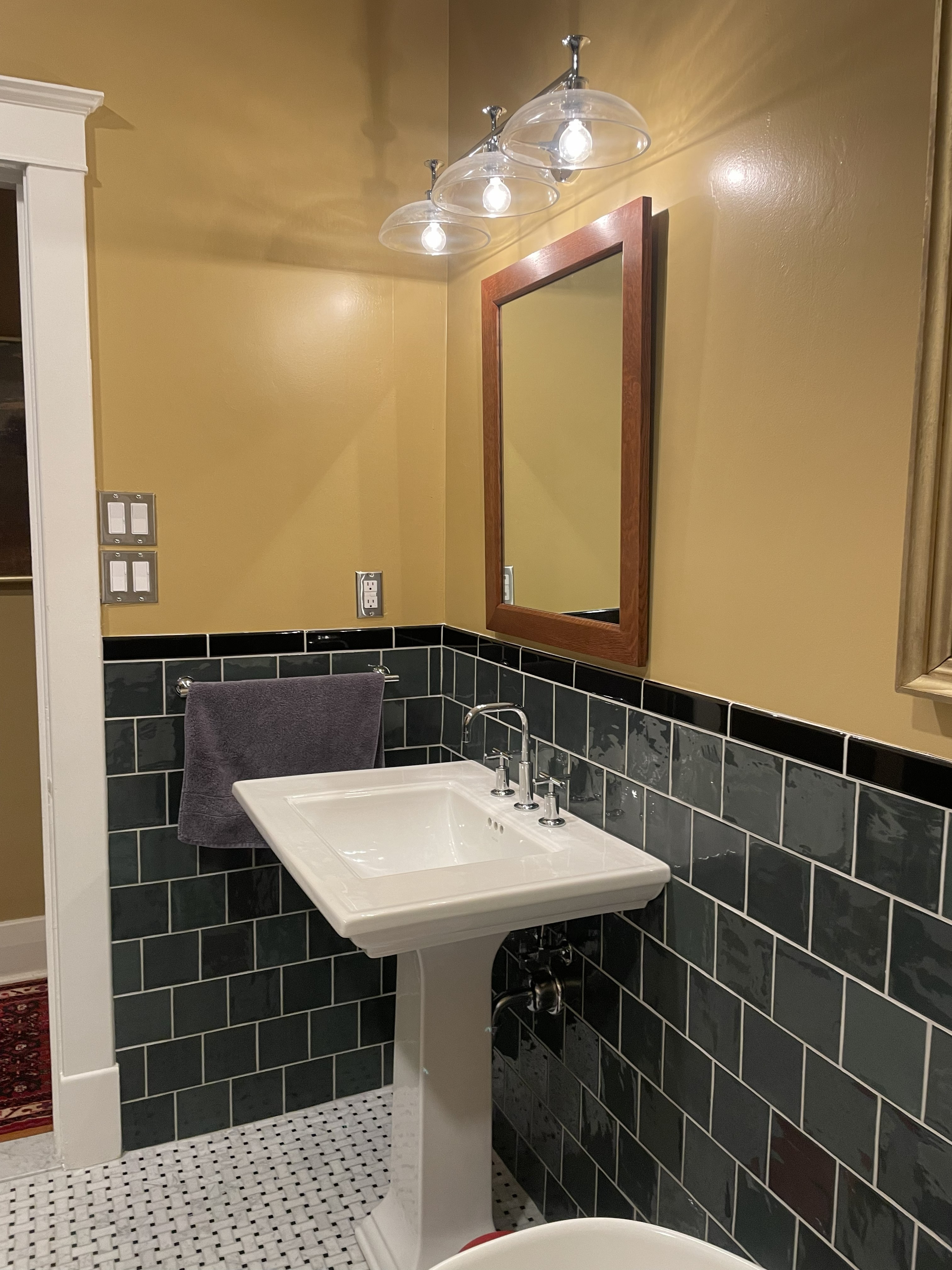 Retro green subway tile bathroom with black border cap and basket weave floor